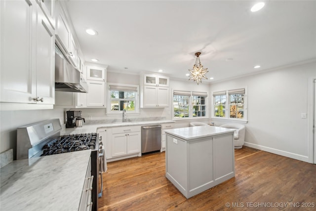 kitchen featuring a kitchen island, stainless steel appliances, light wood-style floors, white cabinetry, and crown molding