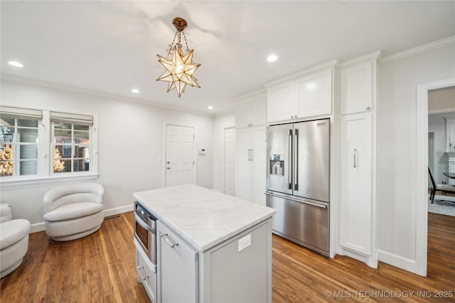 kitchen with white cabinets, ornamental molding, wood finished floors, and stainless steel appliances