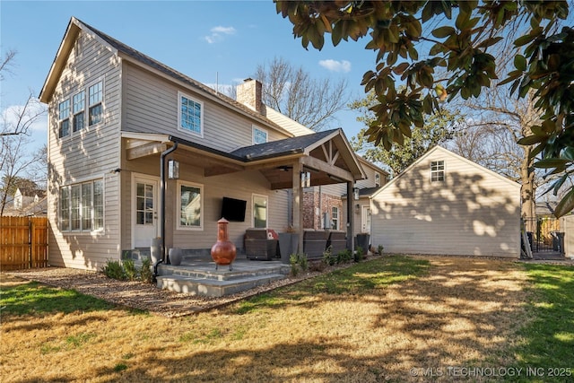 rear view of property featuring a patio area, fence, a lawn, and a chimney