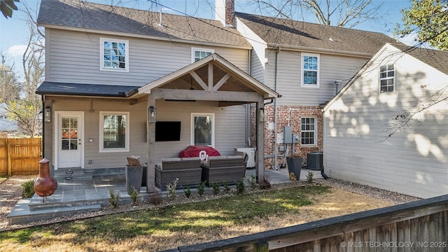 rear view of property with a patio, fence, roof with shingles, an outdoor living space, and a chimney