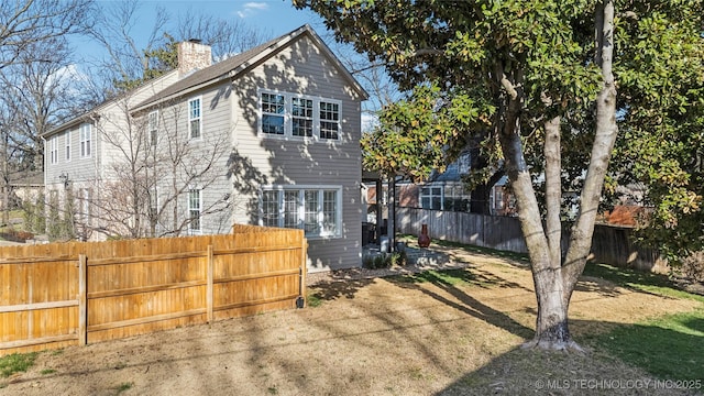 rear view of property with fence private yard, a lawn, and a chimney