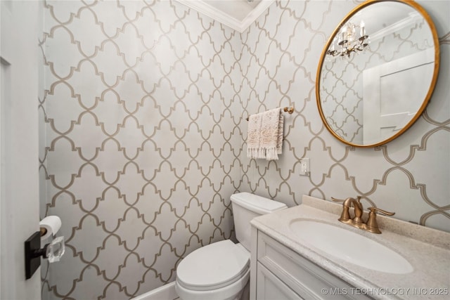 half bathroom with vanity, toilet, and crown molding