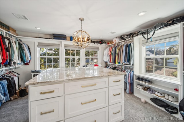 walk in closet with a notable chandelier, visible vents, and light carpet