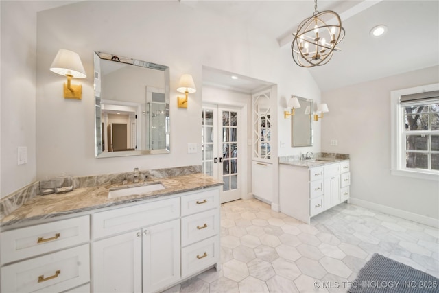 bathroom featuring baseboards, two vanities, lofted ceiling, and a sink