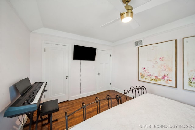 bedroom with dark wood-style floors, visible vents, and ceiling fan