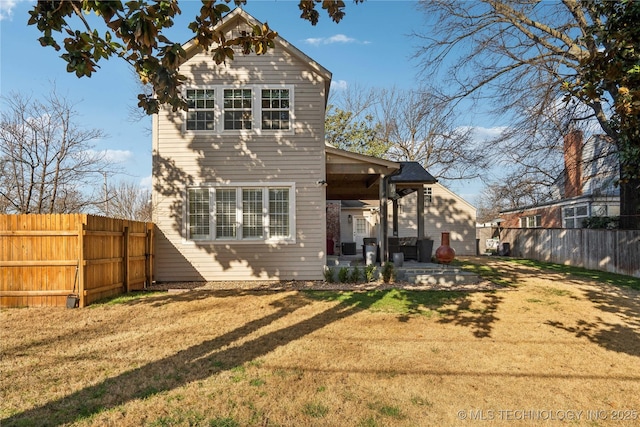 rear view of house with a patio, a yard, and fence