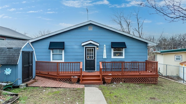 back of property with fence, a wooden deck, a storage shed, an outdoor structure, and a yard