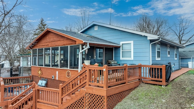 rear view of property featuring a deck, fence, and a sunroom