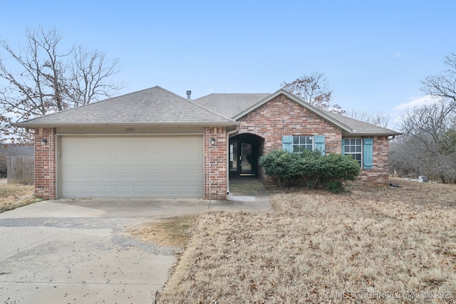 single story home with a garage, brick siding, driveway, and roof with shingles