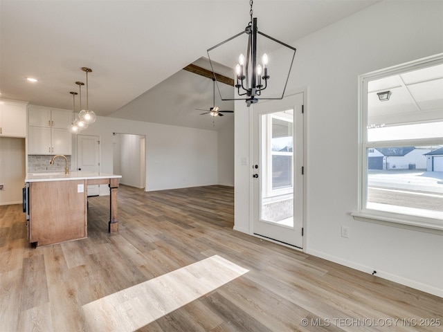 kitchen featuring open floor plan, light wood-style floors, white cabinets, light countertops, and decorative backsplash