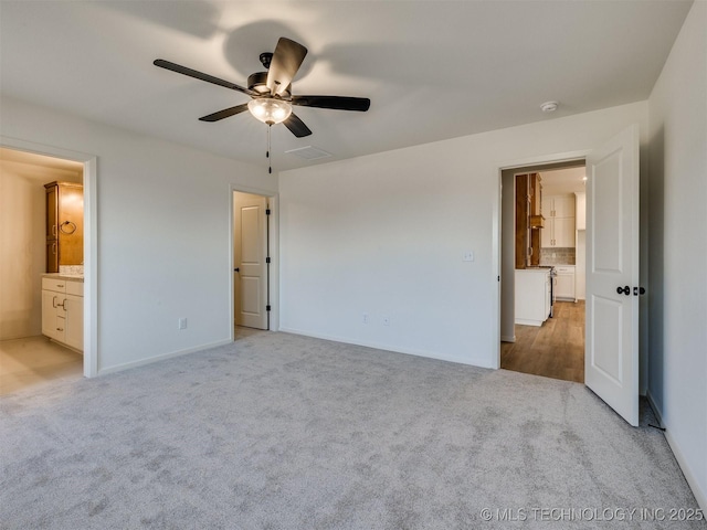 unfurnished bedroom featuring a ceiling fan, ensuite bath, light colored carpet, and visible vents