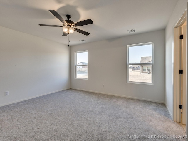 carpeted empty room with visible vents, a ceiling fan, and baseboards