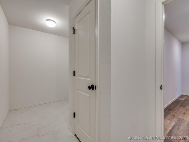 corridor with baseboards and marble finish floor