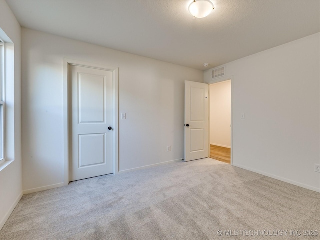 empty room featuring visible vents, baseboards, and carpet