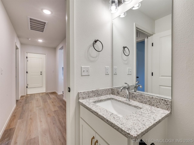 bathroom featuring visible vents, wood finished floors, recessed lighting, baseboards, and vanity