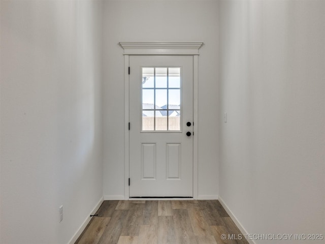 doorway with baseboards and wood finished floors