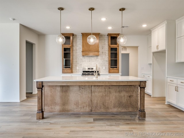 kitchen featuring light countertops, tasteful backsplash, light wood-style floors, and visible vents