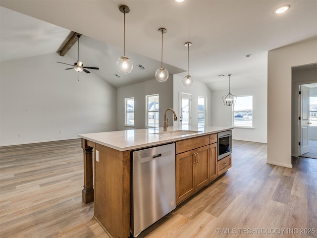 kitchen featuring light wood-type flooring, brown cabinets, a sink, open floor plan, and dishwasher