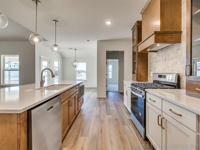 kitchen with brown cabinets, stainless steel appliances, custom range hood, and a sink