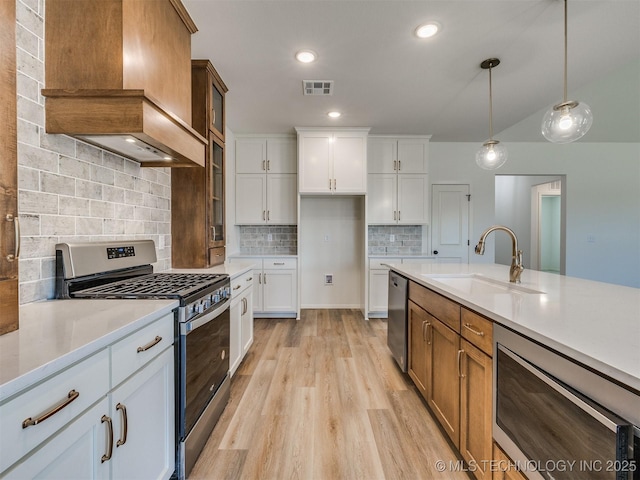 kitchen with premium range hood, a sink, stainless steel appliances, light countertops, and light wood-style floors