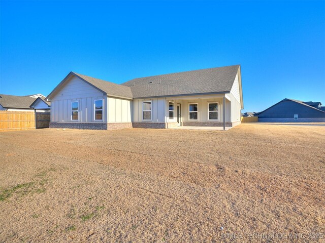 view of front of home with board and batten siding, roof with shingles, and fence