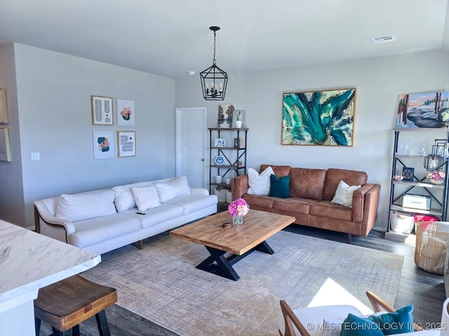 living room featuring a chandelier, visible vents, and wood finished floors