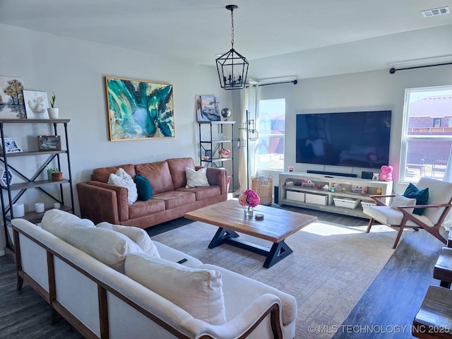 living room featuring visible vents, wood finished floors, and a chandelier