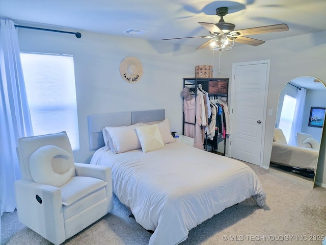 bedroom featuring visible vents, arched walkways, carpet floors, and a ceiling fan