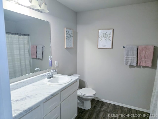 full bath with baseboards, toilet, wood finished floors, and vanity