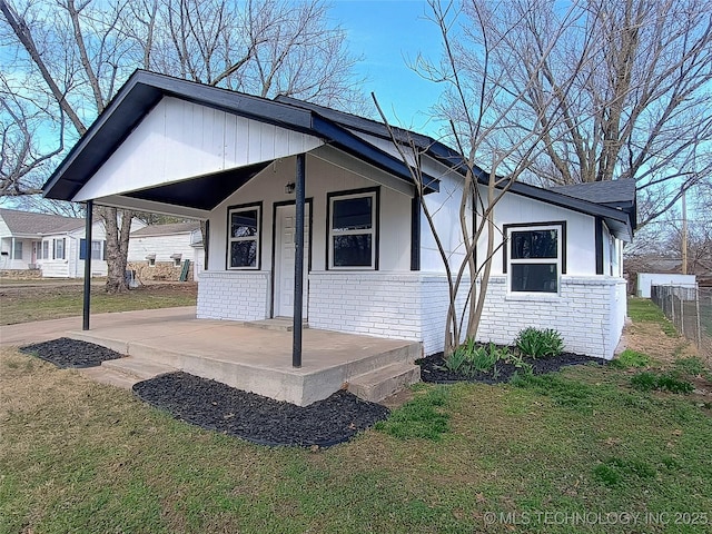 view of front of house featuring fence, driveway, a porch, a front lawn, and brick siding