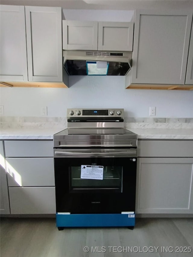 kitchen with light wood-style floors, extractor fan, stainless steel electric range, and gray cabinetry