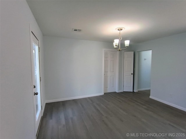 spare room with visible vents, baseboards, a notable chandelier, and dark wood-style floors