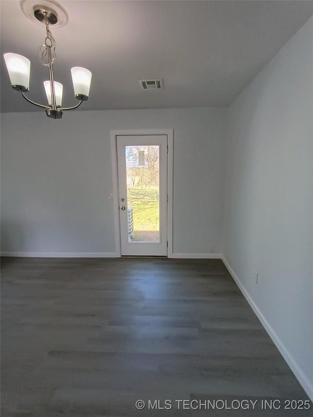 unfurnished room featuring a notable chandelier, visible vents, dark wood-type flooring, and baseboards