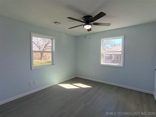 spare room with ceiling fan, visible vents, baseboards, and wood finished floors