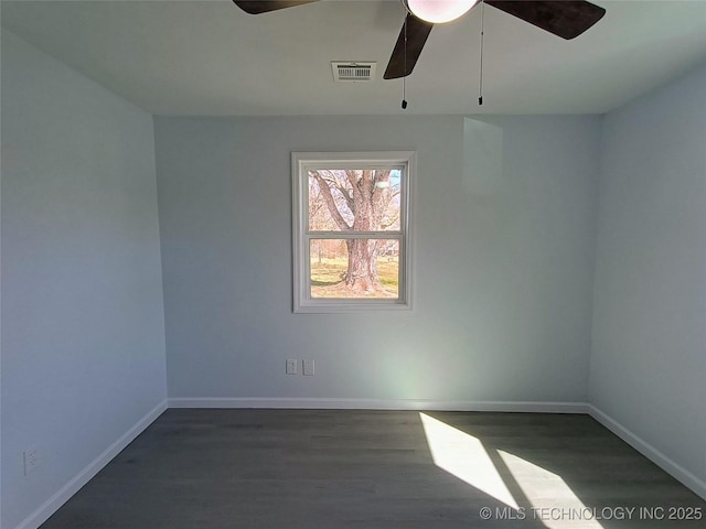 spare room with a ceiling fan, visible vents, wood finished floors, and baseboards