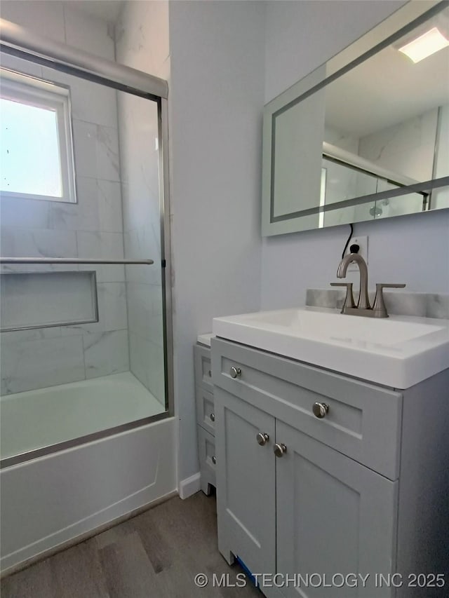 bathroom with vanity, wood finished floors, and shower / bath combination with glass door