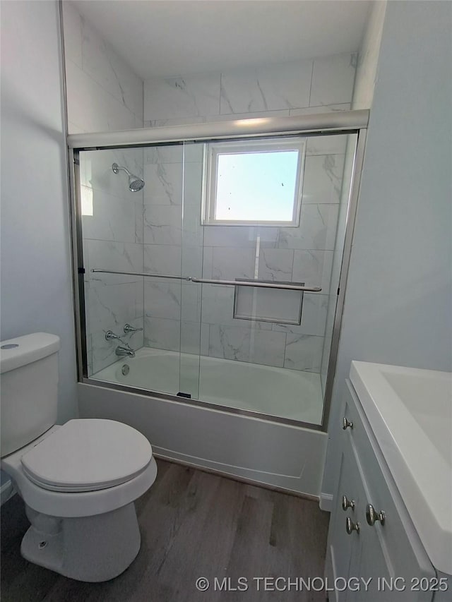 full bathroom with vanity, toilet, wood finished floors, and combined bath / shower with glass door