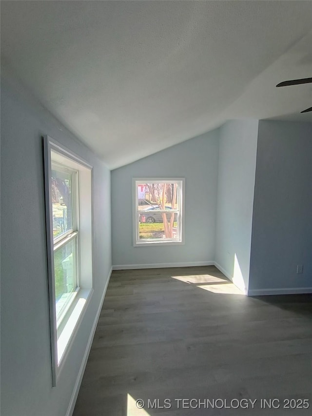 empty room with ceiling fan, baseboards, lofted ceiling, and wood finished floors