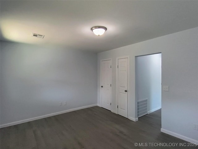 unfurnished bedroom featuring dark wood-type flooring, baseboards, and visible vents