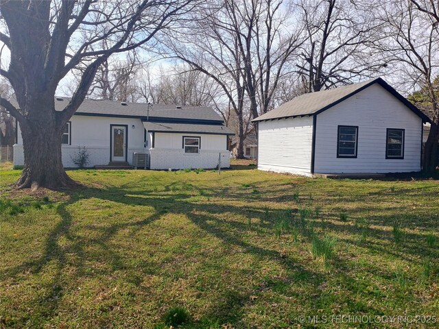 rear view of property featuring brick siding, central air condition unit, and a yard