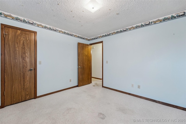 empty room with a textured ceiling, baseboards, and light carpet