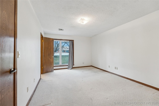 spare room featuring a textured ceiling, baseboards, visible vents, and light carpet