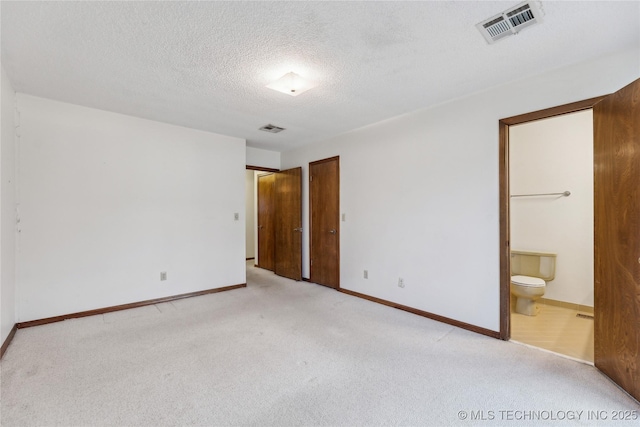 unfurnished bedroom with visible vents, a textured ceiling, ensuite bath, and carpet flooring