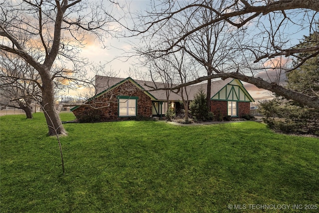 tudor home with brick siding and a lawn