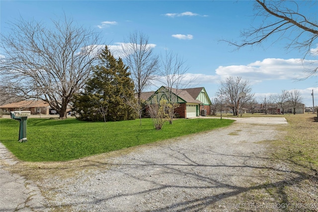 exterior space with brick siding, an attached garage, gravel driveway, and a front yard