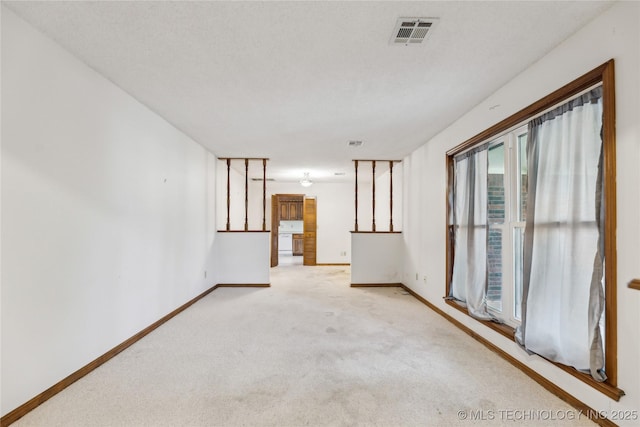 empty room featuring visible vents, light colored carpet, and baseboards