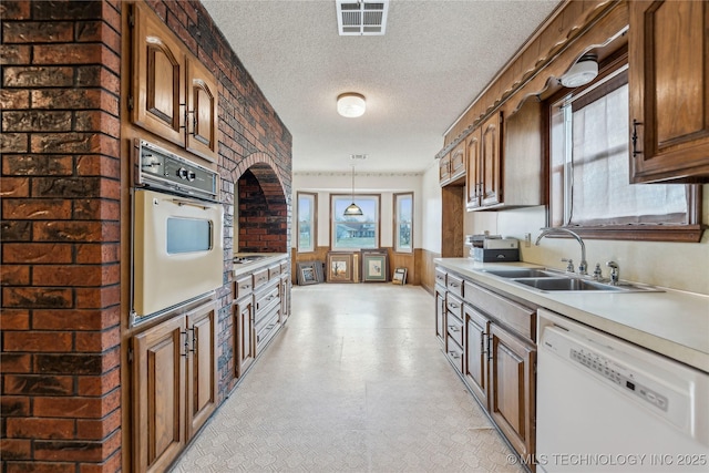 kitchen featuring white appliances, light floors, visible vents, a sink, and light countertops