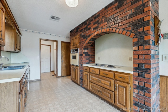 kitchen featuring a sink, visible vents, white appliances, and light countertops