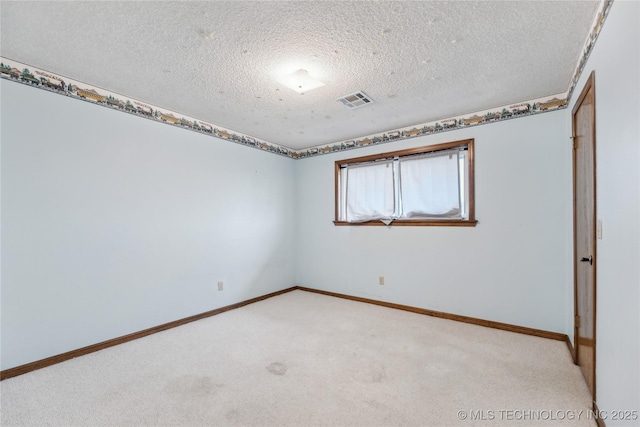 spare room with baseboards, light colored carpet, visible vents, and a textured ceiling