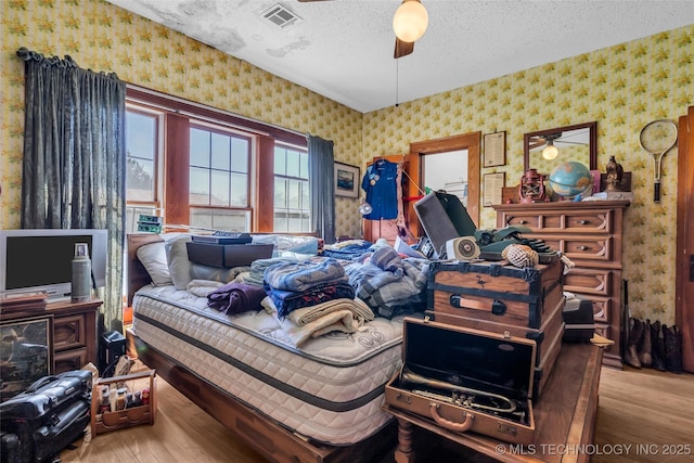20480 Burneyville, Burneyville, OK 73430 - bedroom with visible vents, a textured ceiling, wallpapered walls, and wood finished floors